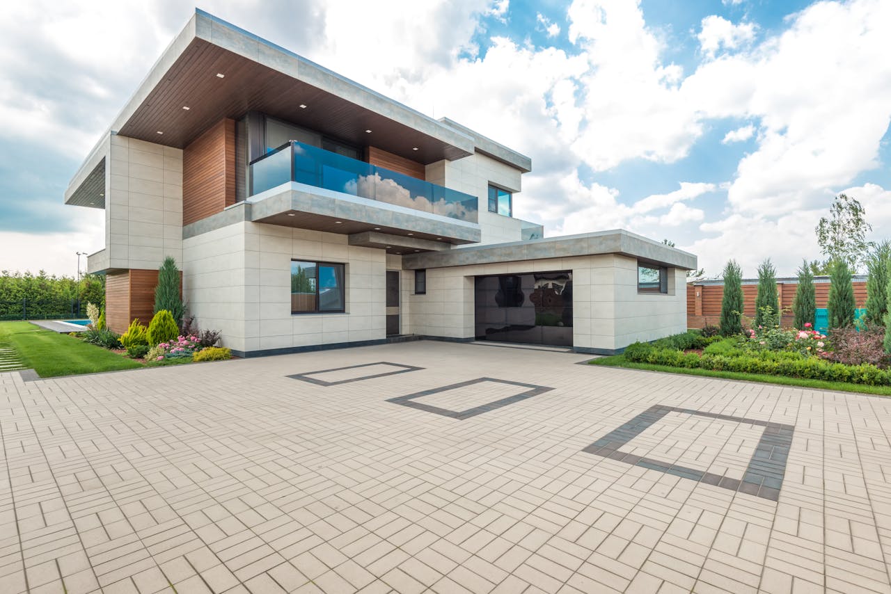 heros-img Elegant modern house exterior with lush greenery and ample driveway space.